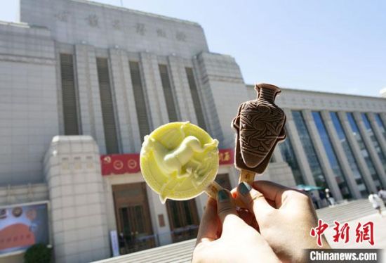 2021年7月30日，游客手拿“銅奔馬”“彩陶瓶”造型的雪糕，在甘肅省博物館前拍照打卡?！「哒?攝