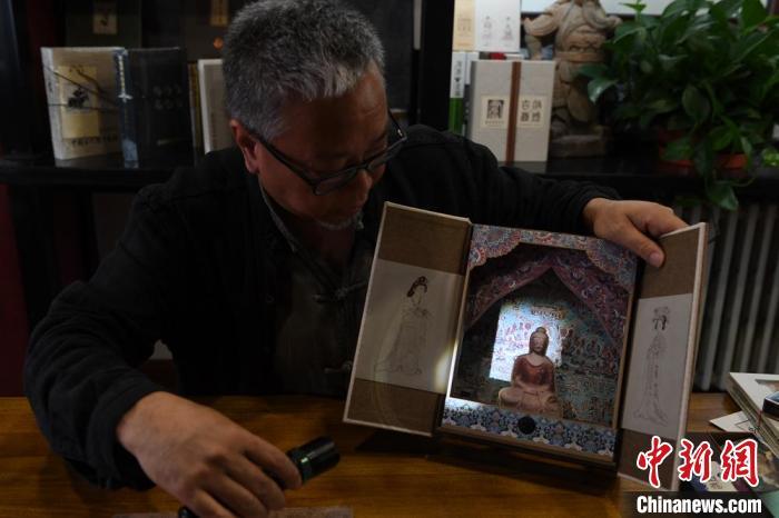 圖為讀者出版集團(tuán)讀者晉林工作室獨(dú)立出品人徐晉林，展示互動(dòng)性強(qiáng)的敦煌題材手工書(shū)。(資料圖) 楊艷敏 攝