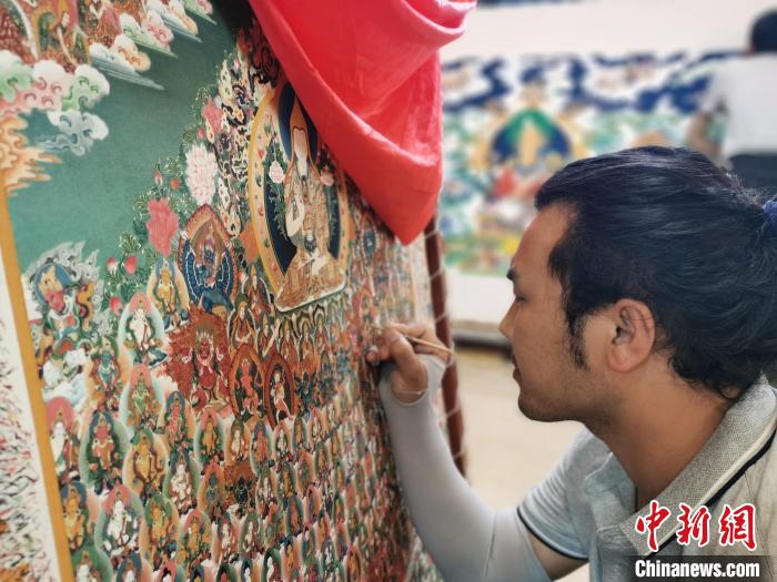 圖為更登才讓的徒弟繪畫唐卡?！?zhí)砀?攝