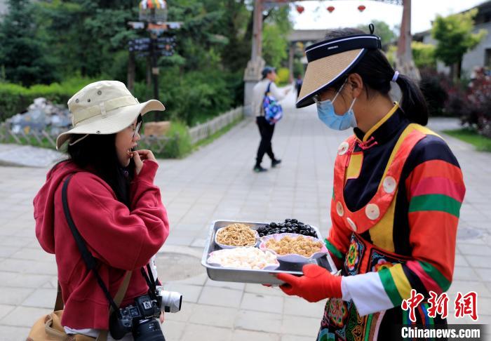 圖為身穿土族服飾的女性介紹當地特色小吃?！⊙Φ?攝