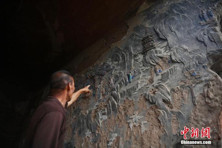7月15日，甘肅省平?jīng)鍪袥艽h百里石窟長廊羅漢洞石窟內(nèi)，該窟文保員郭建平介紹窟內(nèi)石刻彩繪壁畫。郭建平家中三代人曾自發(fā)保護(hù)羅漢洞石窟。羅漢洞石窟遺存40余個(gè)窟龕，以北魏至清代風(fēng)格為主。中新社記者 李亞龍 攝
