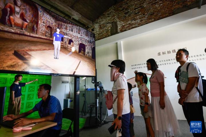 7月22日，游客體驗“尋境敦煌——數(shù)字敦煌沉浸展”后，在虛擬演播廳拍攝一段真人與洞窟虛擬場景交互的視頻。新華社記者 郎兵兵 攝</p>
<p>
