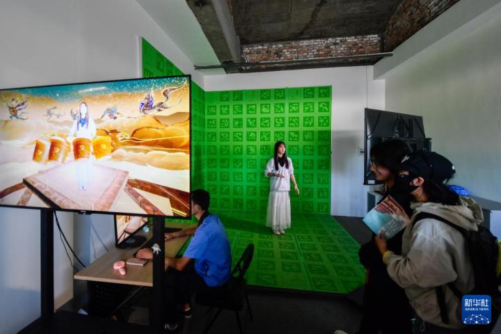 7月22日，游客體驗“尋境敦煌——數(shù)字敦煌沉浸展”后，在虛擬演播廳拍攝一段真人與洞窟虛擬場景交互的視頻。新華社記者 郎兵兵 攝</p>
<p>